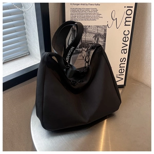 Détail du sac bandoulière en nylon noir avec sangle 'FASHION' sur table en métal