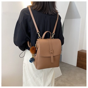 Dettaglio di uno zaino vintage marrone indossato da una modella in una stanza dal design minimale