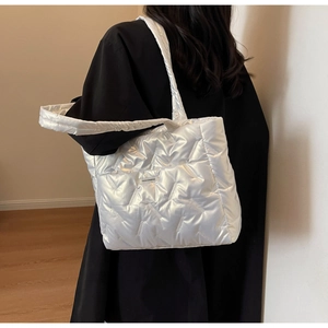 Detailed view of silver quilted tote bag with metallic sheen and woven fashion label