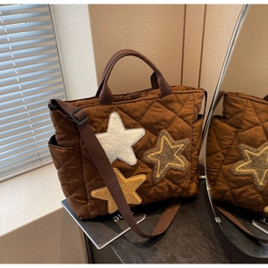 Makro-Detail der dunkelbraunen Stepptasche mit Stern-Patches und Nylon-Gurt