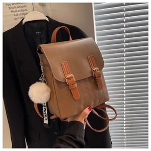 Detail eines braunen Kunstleder-Rucksacks mit Rautensteppung und flauschigem Anhänger