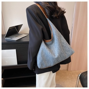 Detail of blue denim tote bag with brown leather trim and spacious interior for daily use
