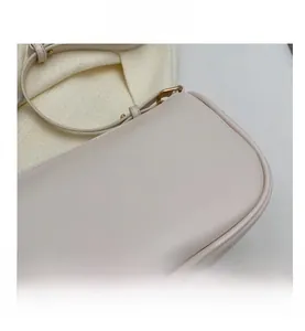 Detailed close-up of smooth beige leather texture and precision stitching on a shoulder bag