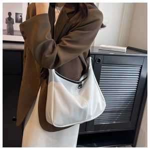 Vue détaillée du sac hobo blanc en croissant avec bandoulière noire sur l'épaule