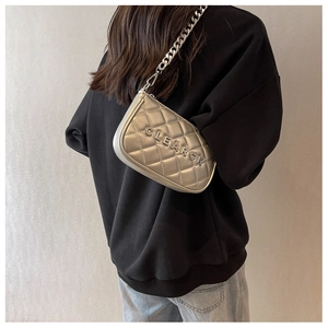 Silver quilted crossbody bag featuring heavy chain strap and metallic finish on model