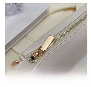 Close-up of smooth gold zipper detail on premium cream white leather pillow bag