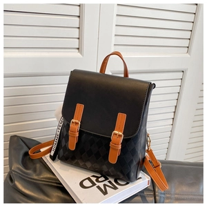 Detail eines schwarzen gesteppten Rucksacks mit braunen Lederriemen und Plüschanhänger