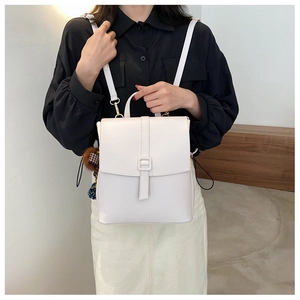 Dettaglio di uno zaino bianco minimalista in pelle PU con un ciondolo decorativo raffinato