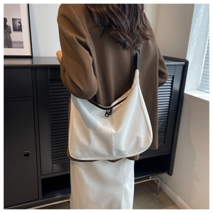 Détail du sac hobo en toile blanche montrant la bandoulière noire et la fermeture éclair