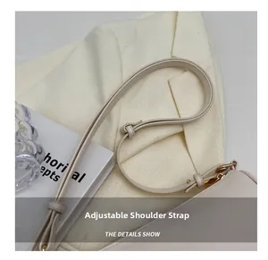 Close-up of beige leather bag with adjustable strap and golden metal buckle details