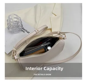 Internal capacity of cream-colored pillow bag showing phone, wallet and makeup inside