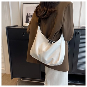 Détail d'un sac cabas demi-lune en cuir blanc avec fermeture éclair noire contrastée sur l'épaule