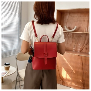 Modella che indossa uno zaino vintage in pelle rossa con patta e pompon decorativo