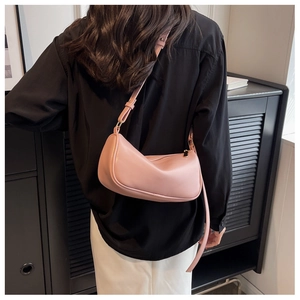 Chic pink crescent shoulder bag shown on model with adjustable strap and smooth finish