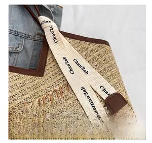 Détail de la texture d'un sac cabas en paille avec bordure en cuir marron et broderie