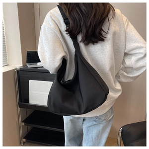 Vue de dos d'un mannequin portant un grand sac bandoulière croissant en nylon noir réglable