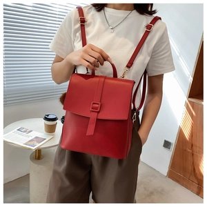 Scatto all'aperto di uno zaino vintage rosso acceso con patta e fibbia in stile casual