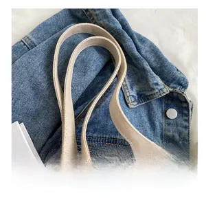 Close-up of woven cream strap and brown leather patch on minimalist canvas tote bag