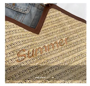 Détail du sac cabas en paille avec broderie Summer et bordure en cuir marron