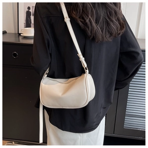Minimalist cream white cylinder crossbody bag with adjustable strap in urban setting