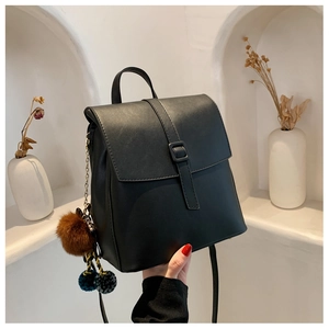 Dettaglio di uno zaino nero in pelle PU con ciondoli decorativi in peluche e chiusura a patta