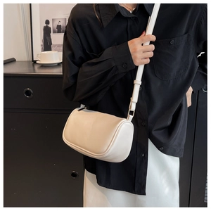 Detail of a creamy beige cylinder crossbody bag with gold zippers and adjustable strap