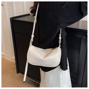 Detailed close-up of a cream-colored leather crossbody bag with elegant gold hardware zipper