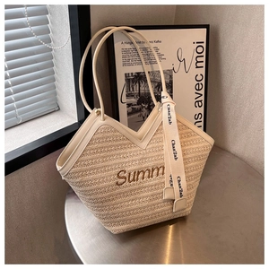 Détail d'un sac cabas en paille avec broderie Summer et foulard décoratif en soie noué