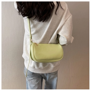 Detail view of mint green synthetic leather crossbody bag with golden zipper and strap