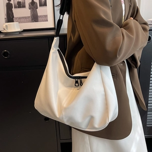 Sac hobo blanc minimaliste avec bandoulière noire présenté dans un intérieur contemporain