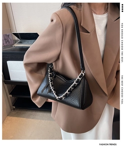 Detail of black pebbled leather shoulder bag with chic silver chain and sleek zipper strap