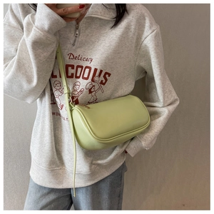 Detail view of the pale green cylinder crossbody bag with golden zipper and leather strap
