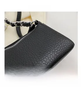 Close-up of black ostrich-textured leather bag featuring silver metal chain strap
