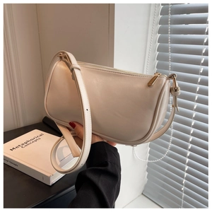 Close-up of cream leather pillow bag with gold zipper and adjustable shoulder strap