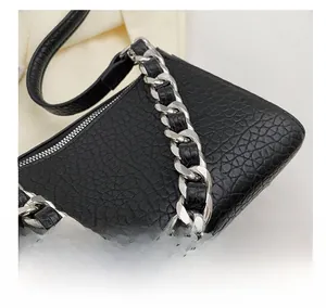 Detail of black leather underarm bag with thick silver chain strap and zipper