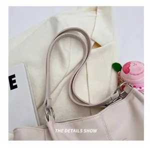 Dettaglio della borsa tote beige con anelli metallici e ciondolo a cuore in peluche