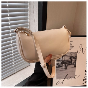 Detail shot of cream white PU leather pillow bag with gold zipper and adjustable strap