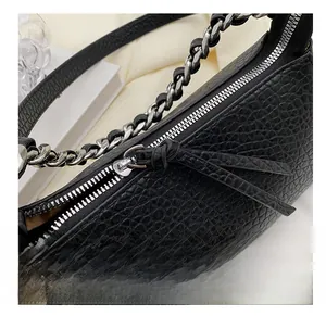 Detail shot of smooth silver zipper and crocodile leather texture on the black handbag