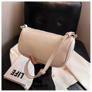 Detail of a beige cylinder shoulder bag with gold zipper and smooth leather finish