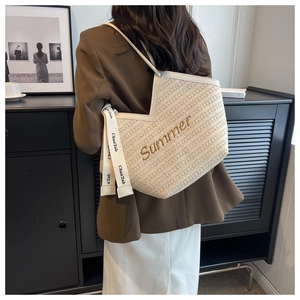 Détail du sac cabas en paille beige avec broderie Summer et ruban décoratif élégant