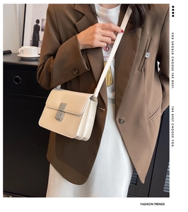 Detail view of cream leather crossbody bag featuring silver buckle and accordion side gussets