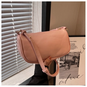 Close-up of a light pink leather cylinder shoulder bag with elegant gold hardware details