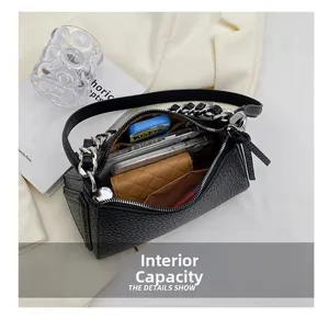 Interior view of black pebbled leather triangle bag showing storage for phone and daily items