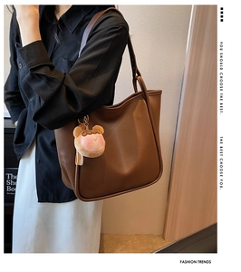 Brown leather tote bag with a cute pink plush charm for versatile summer styling