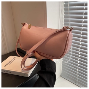Detailed view of pink cylindrical pillow bag with gold zipper and leather strap