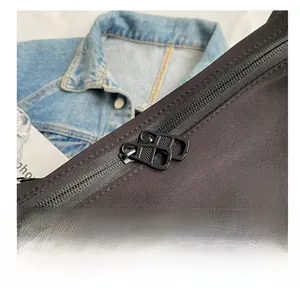 Detailed macro shot of smooth dual metal zippers on a black canvas crossbody bag