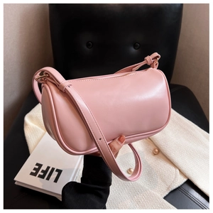 Pink cylinder pillow bag made of smooth leather held by a model in a classic setting
