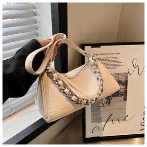 Detalle del bolso almohada en cuero blanco crema con textura craquelada y cadena de plata