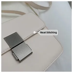 Close-up of neat stitching and embossed stripe metal lock on beige leather bag
