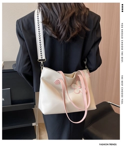 Close-up of cream tote bag with pink daisy ornament and striped wide shoulder strap